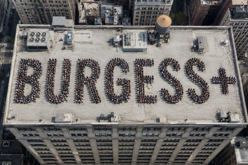 Aerial view of people standing on a building forming the word BURGESS+